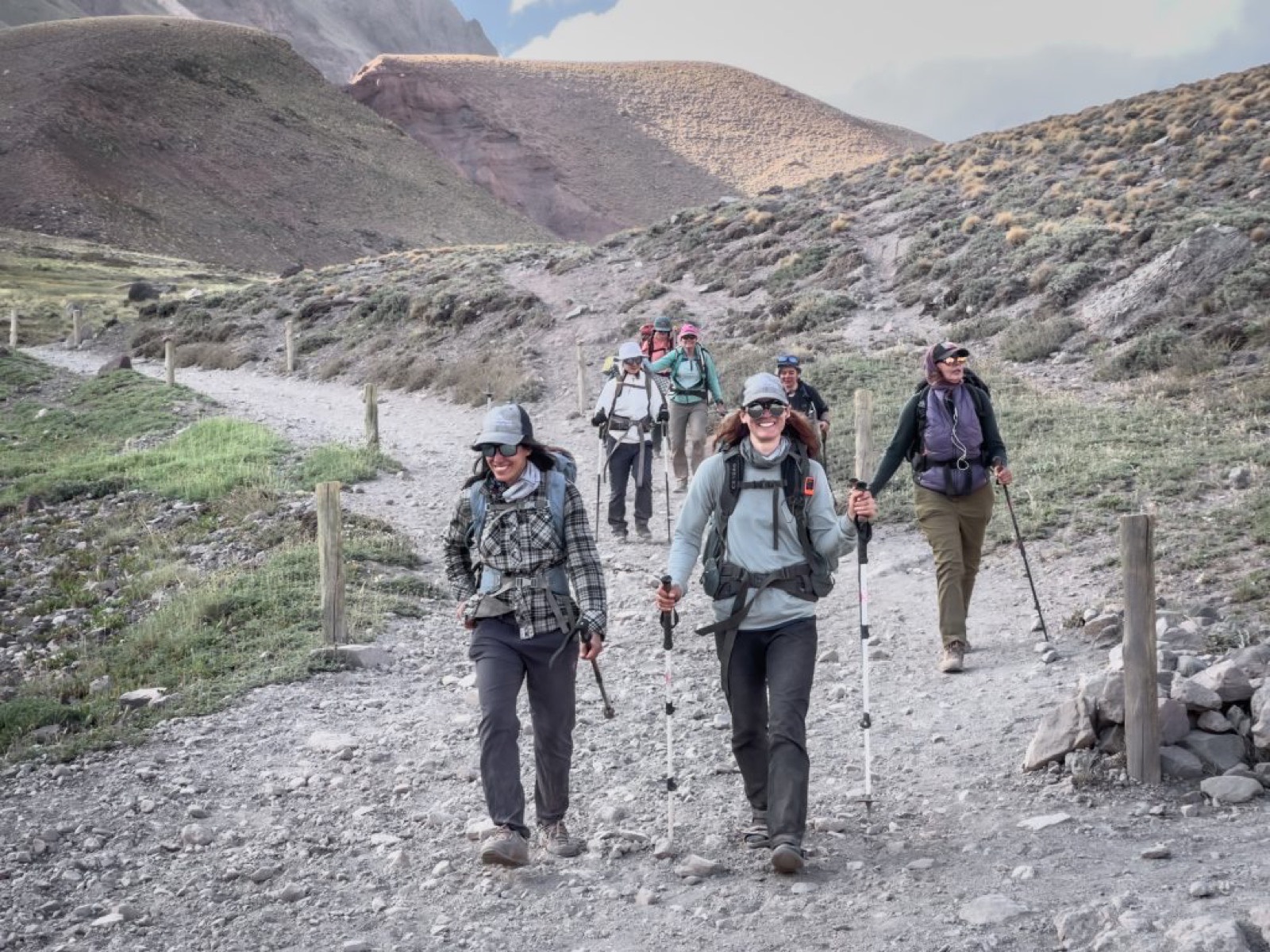 An AWE team smiling as they hike the trail toward Aconcagua