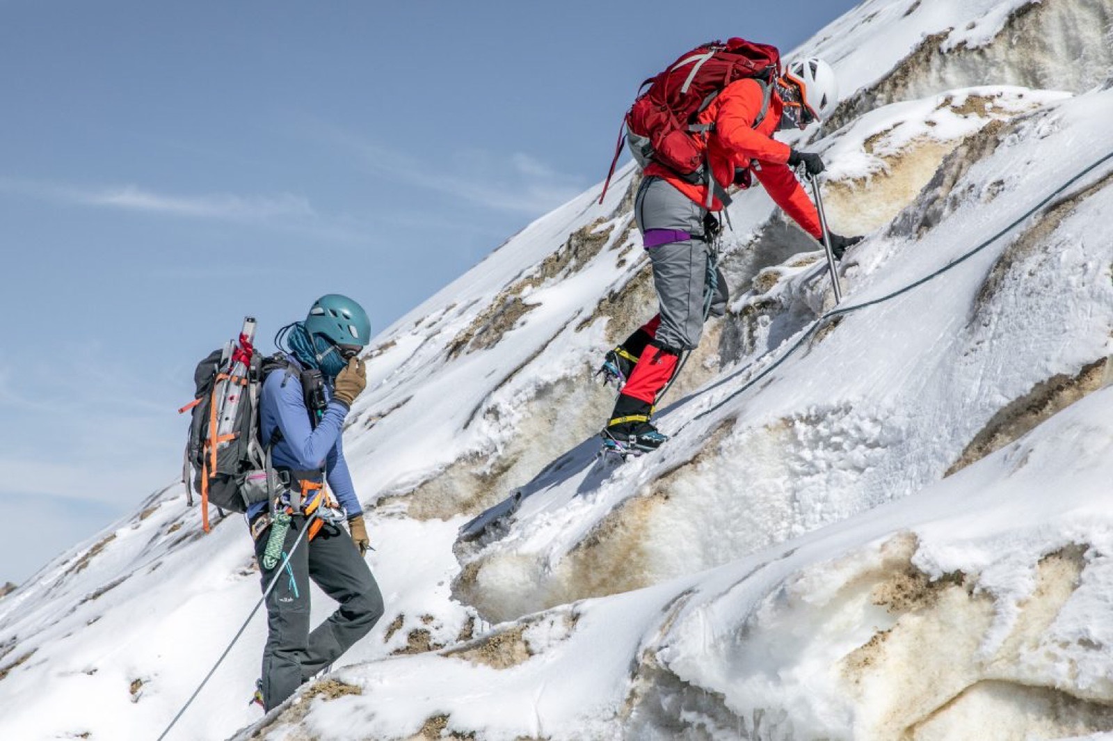 Two climbers on a fixed line crossing steep ice on Mount Baker