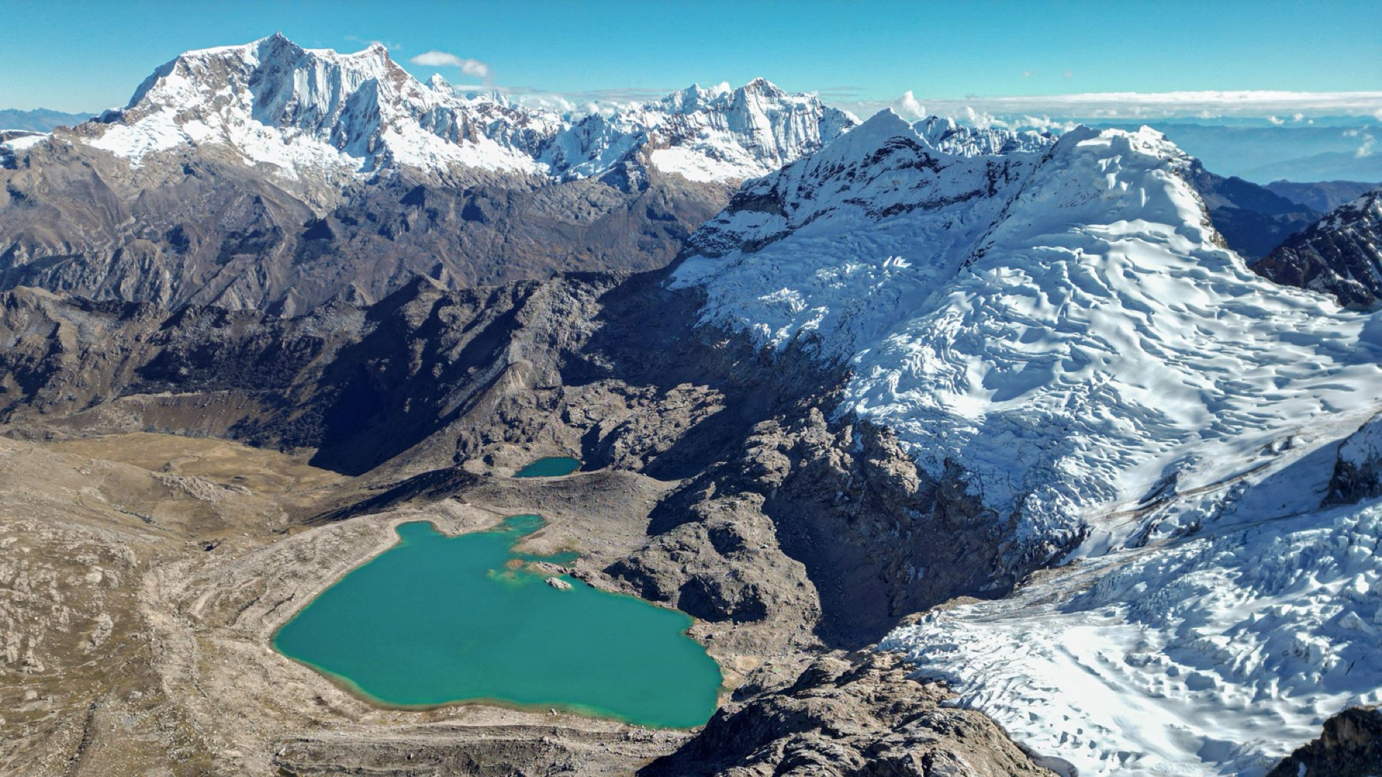 Aerial view of a turquoise lake below glaciated peaks in Peru