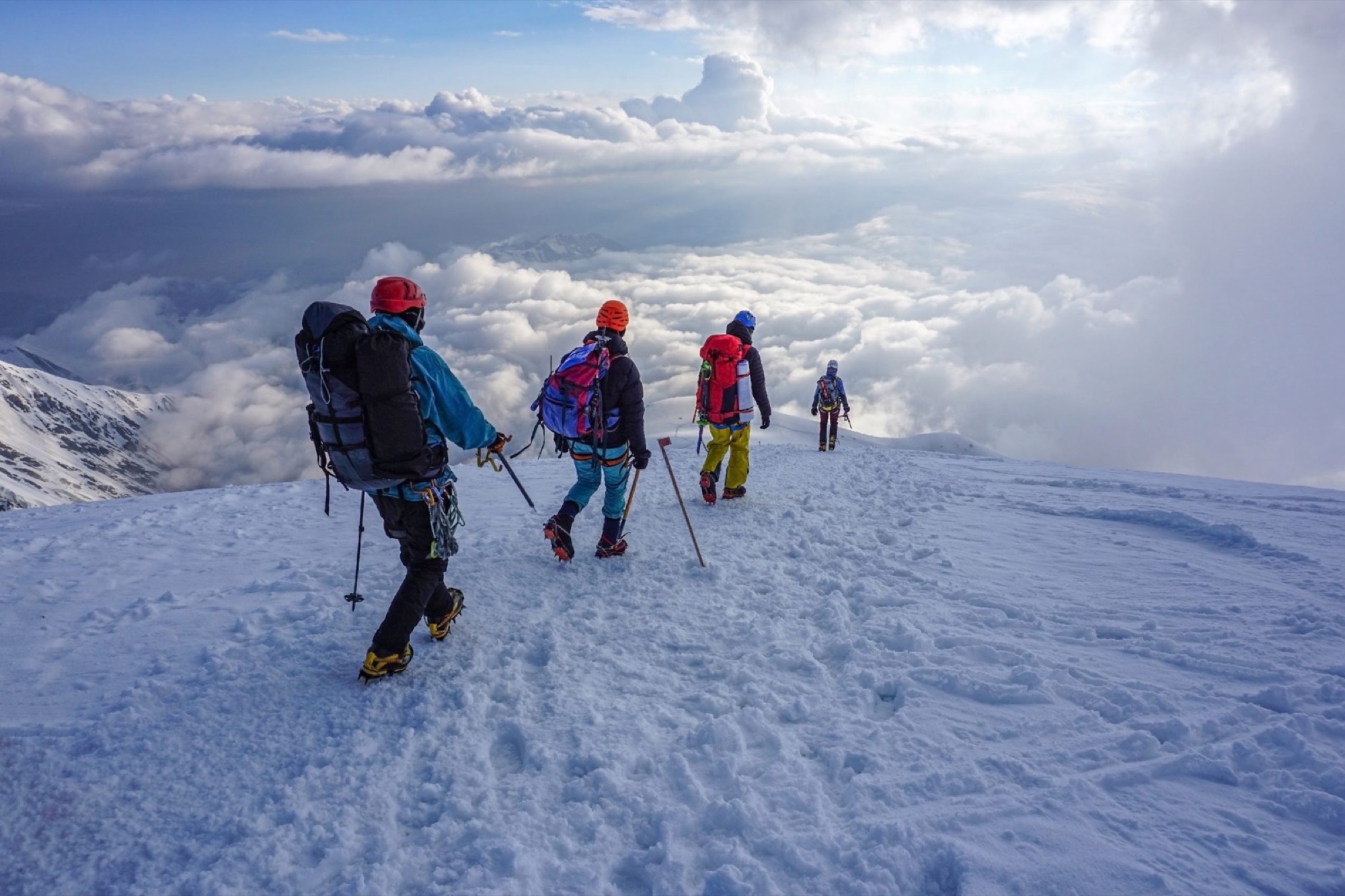 Climbers on a snow ridge above the clouds on Lenin Peak