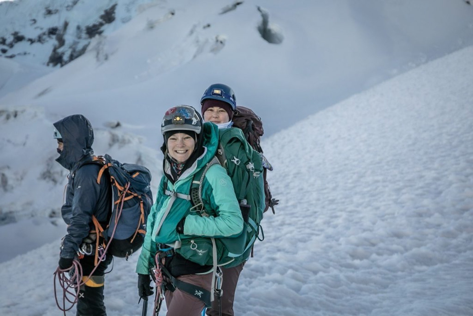 Three smiling climbers roped together on a snowy glacier in the Cordillera Blanca